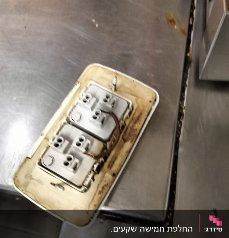 Electrical outlet with exposed wiring on metal surface